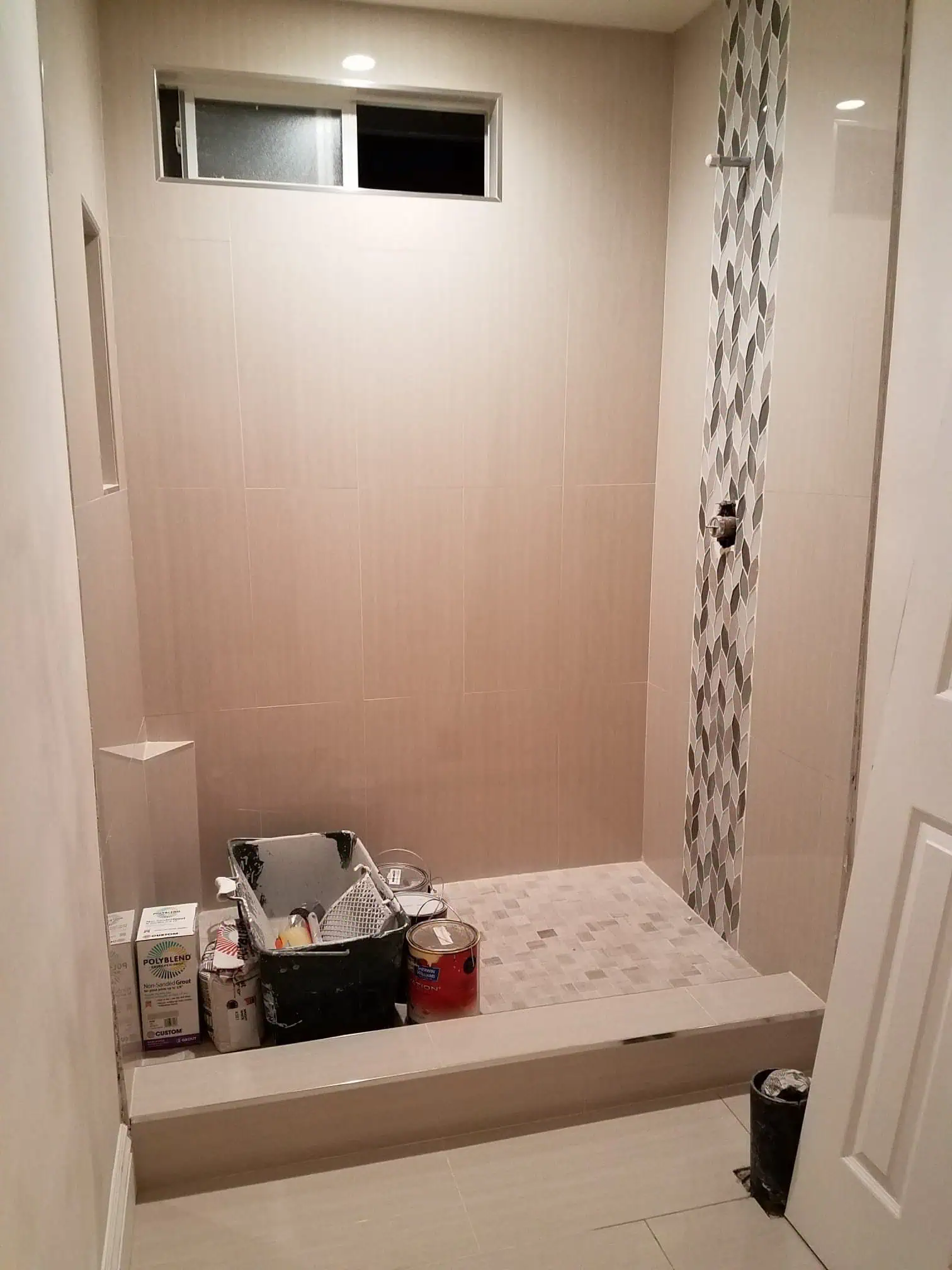 Modern bathroom with tiled shower area and small window for ventilation.