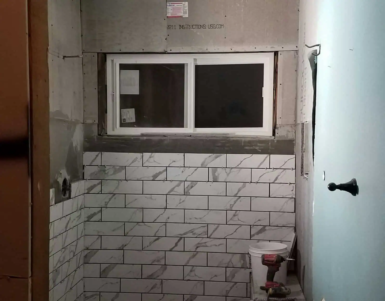 Bathroom under renovation with tile walls and window installation.