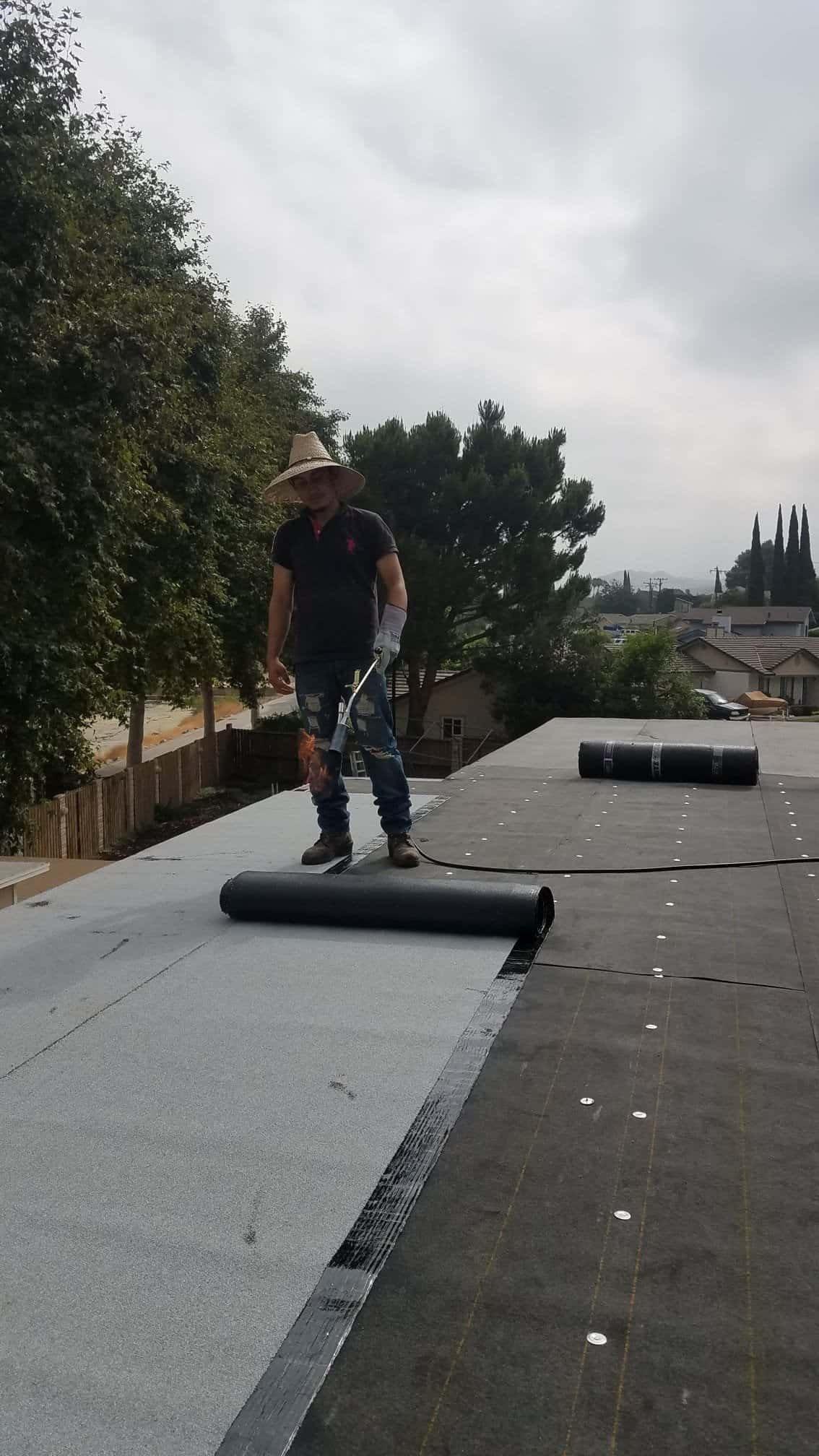 Worker installing roofing membrane on commercial building roof.