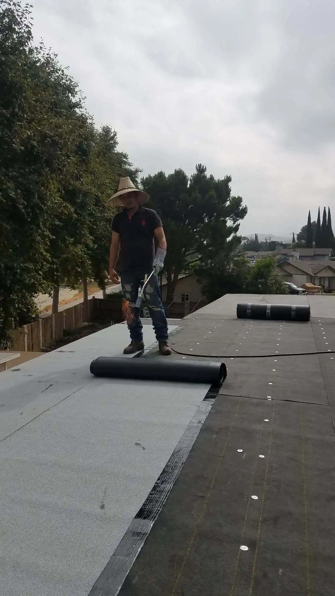 Worker installing roofing membrane on commercial building roof.