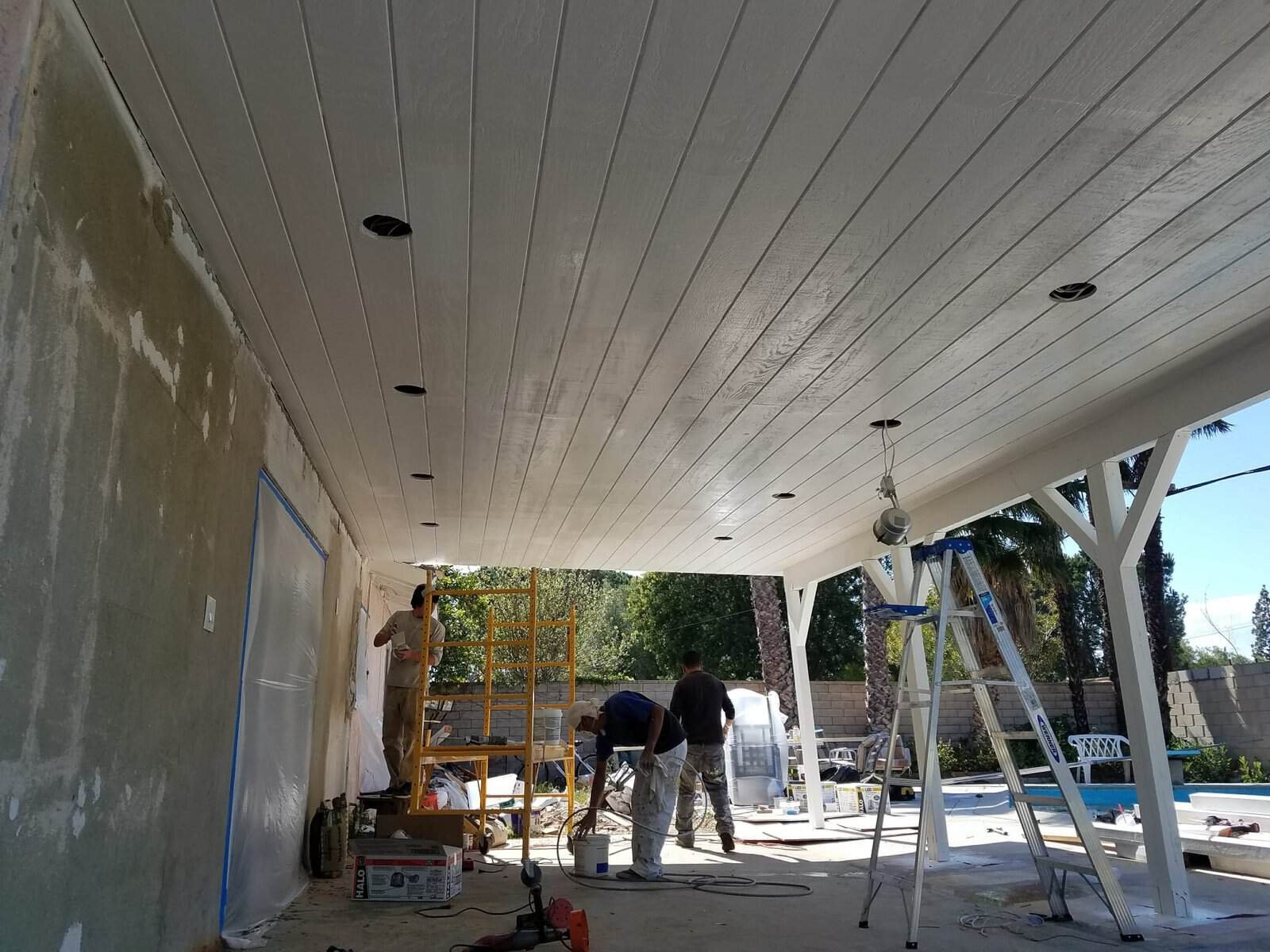 Home porch construction with workers and tools in progress.
