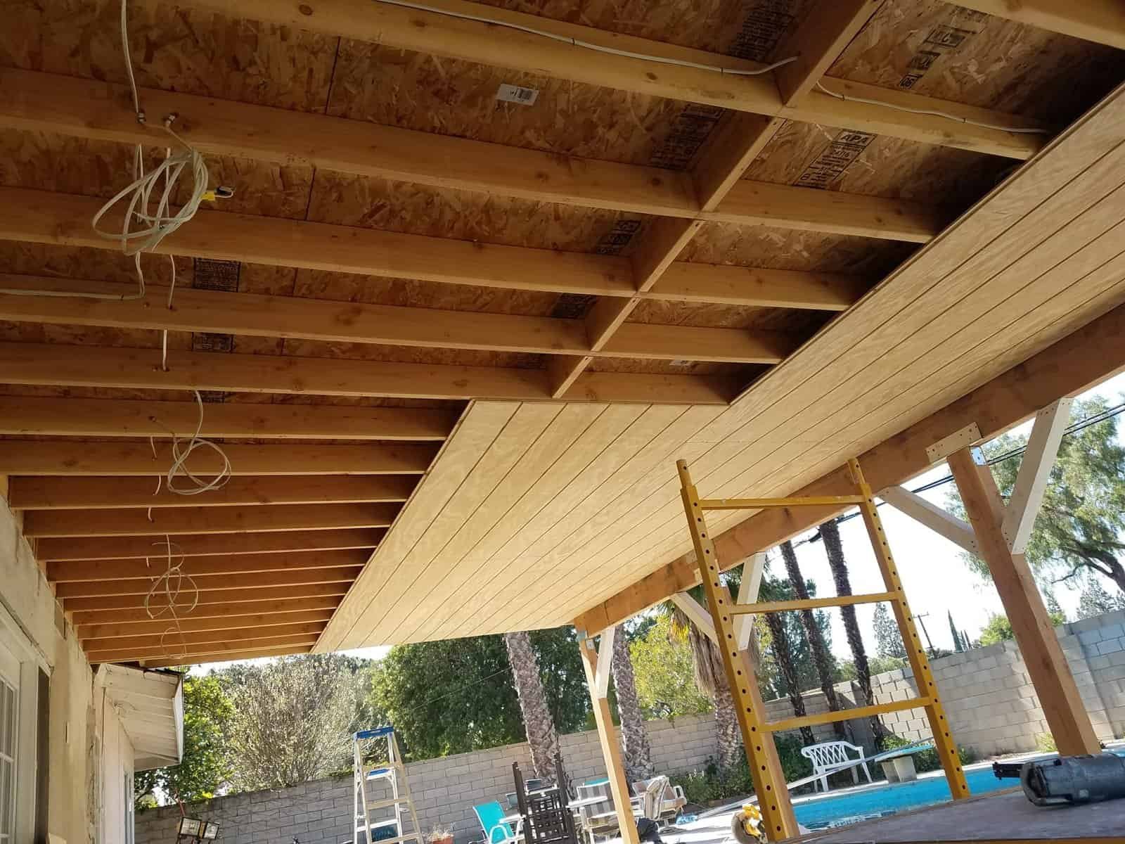 Wooden porch construction with scaffolding and ceiling framework.