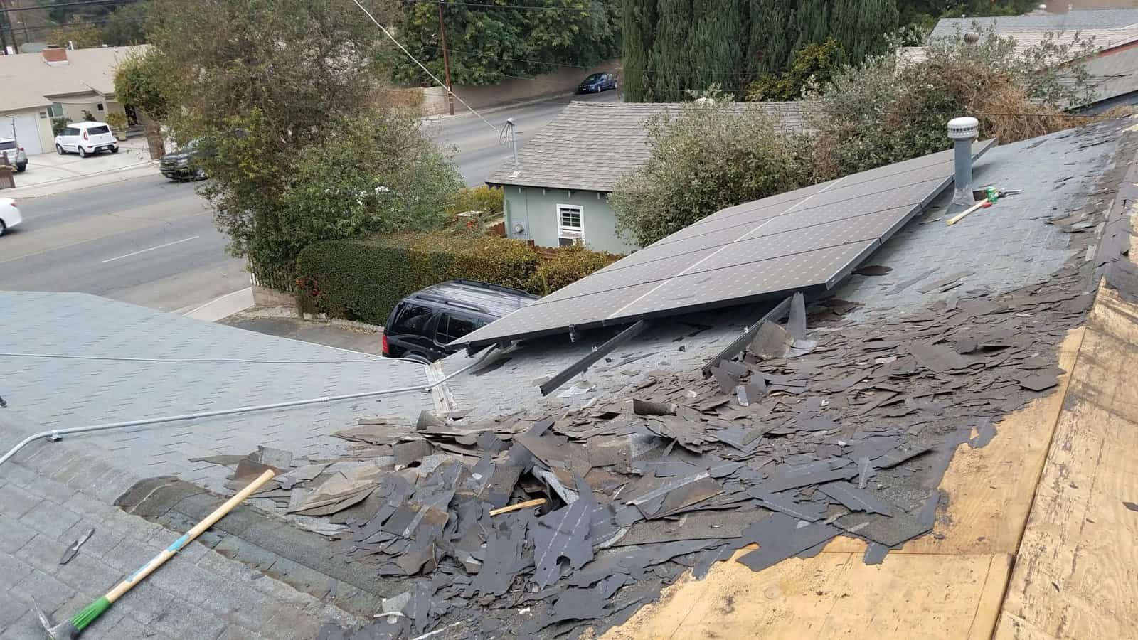Damaged roof with broken shingles and solar panels after storm.